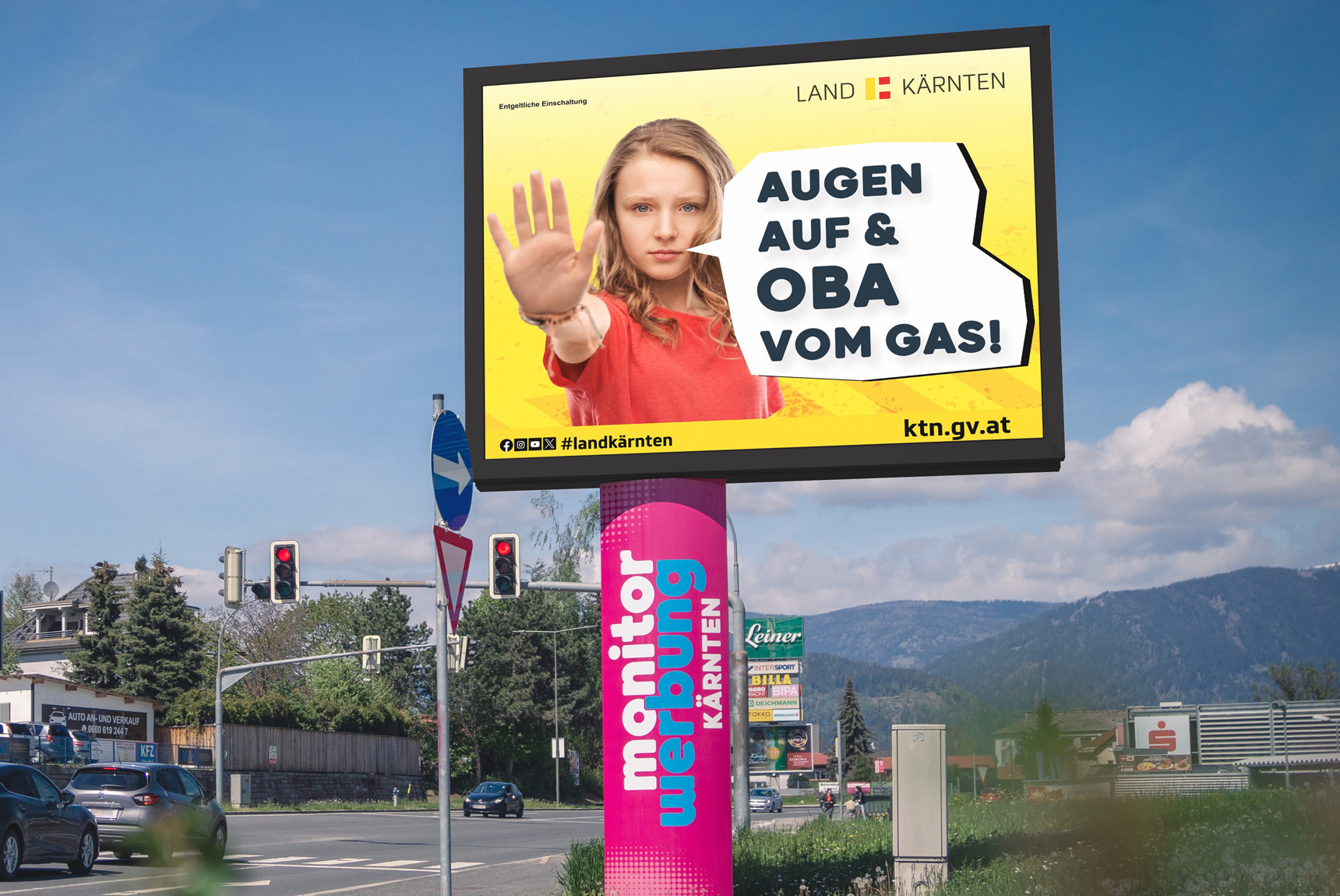 Eine LED Wall neben der Straße. Zu sehen am Screen eine Grafik mit dem Titel "Augen auf, Auto ist da!"