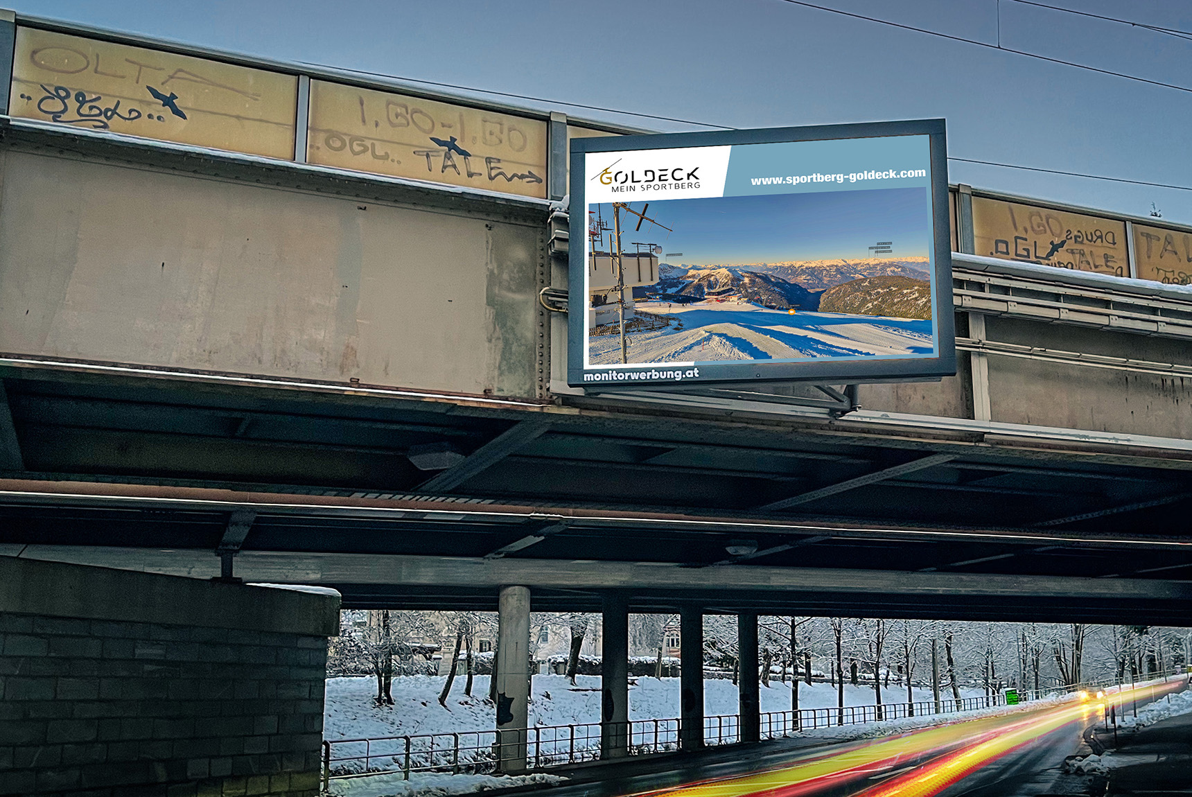 Eine LED-Wall auf einer Eisbahnbrücke über einer Straße. Zu sehen ist die Webcam des Skigebiets Goldeck.